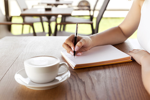 Woman hand writing on notebook in the cafe