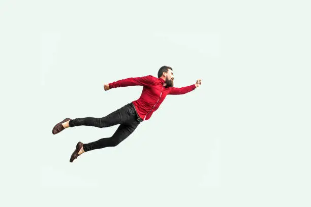 Superman style. Enthusiasm concept. strong bearded businessman felt himself a superhero and flying up. indoor studio shot isolated on gray background.