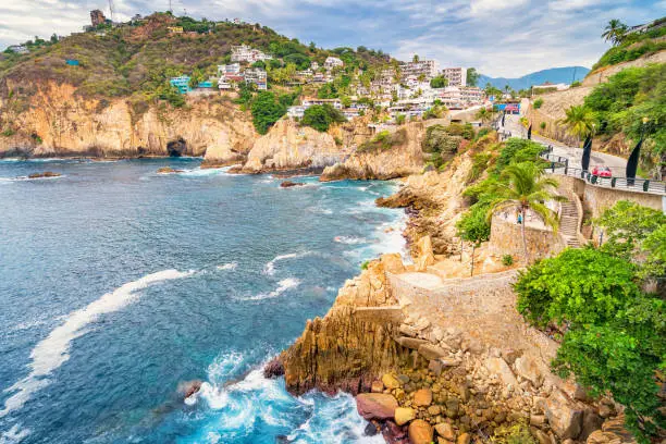 Stock photograph of rocky coastline with promenade in Acapulco, Guerrero, Mexico.