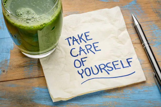 take care of yourself - inspirational handwriting on a napkin with a glass of green juice