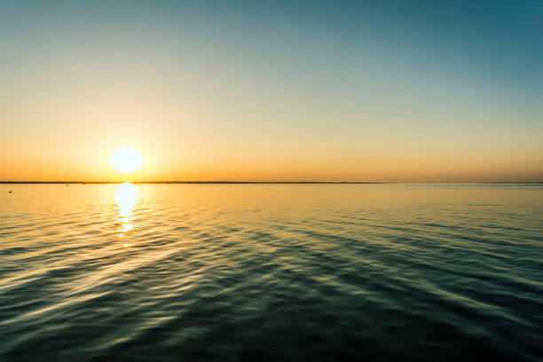 istock colorful sunset over water surface, evening sun over the bay, summer sky without clouds 1023775082