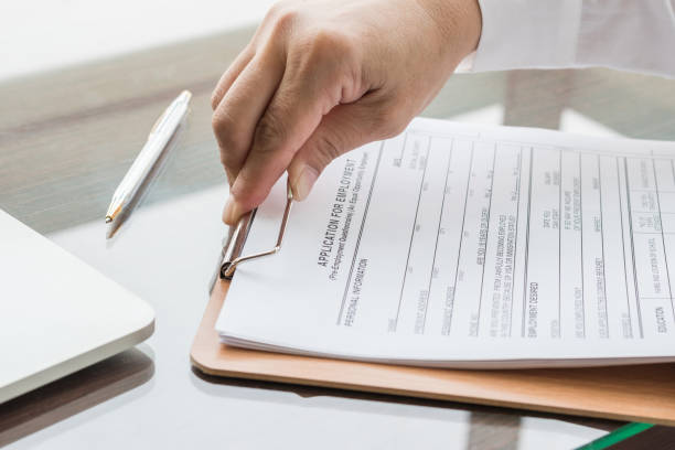 istock Applicant filing in company application form document applying for job, or registering claim for health insurance 1023798400