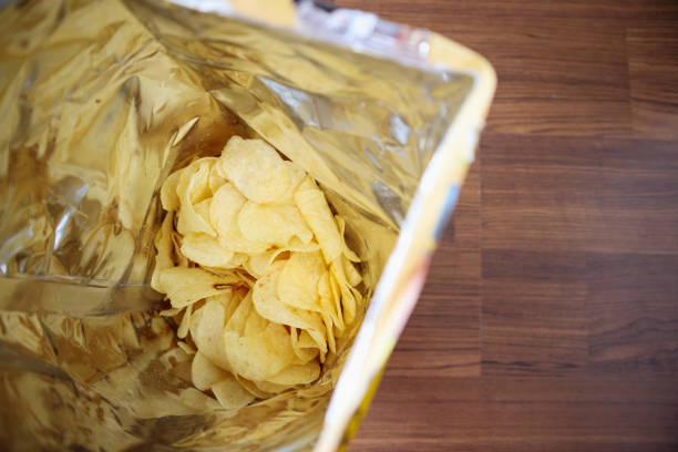 istock Potato chips in open snack bag close up on table floor 1023798412
