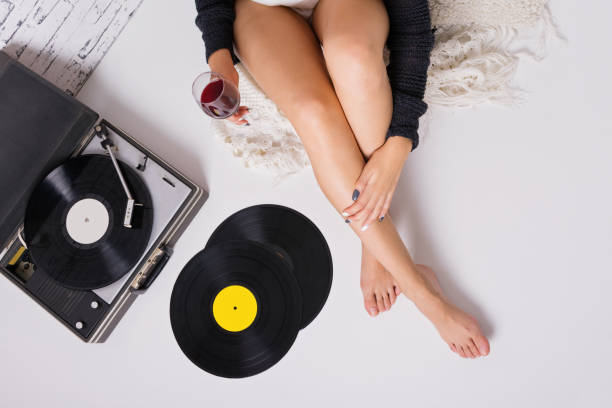 Mujer tomando vino y escuchando música en un tocadiscos y discos de vinilo - foto de stock