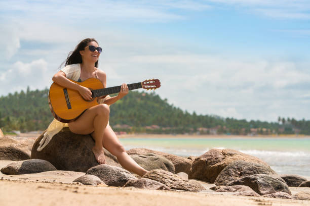 istock Young woman with guitar on beach 1023829106