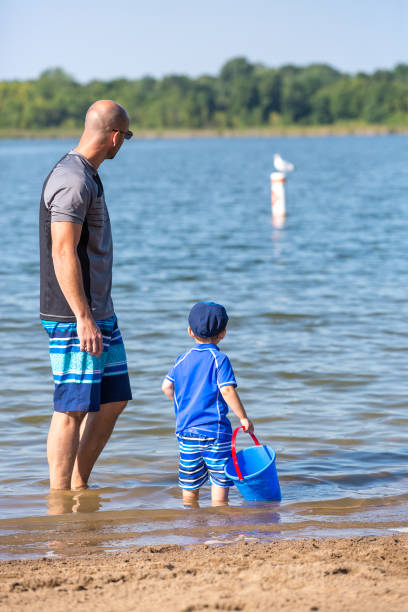 istock Father & Son At Beach Looking At Seagull on Buoy 1023840024