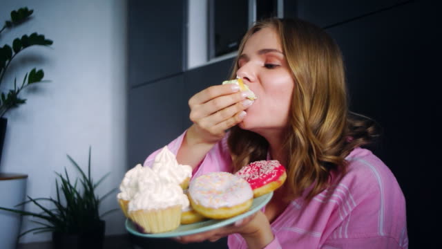 Eating woman enjoy cream cupcake. Woman tasting sweet cookies