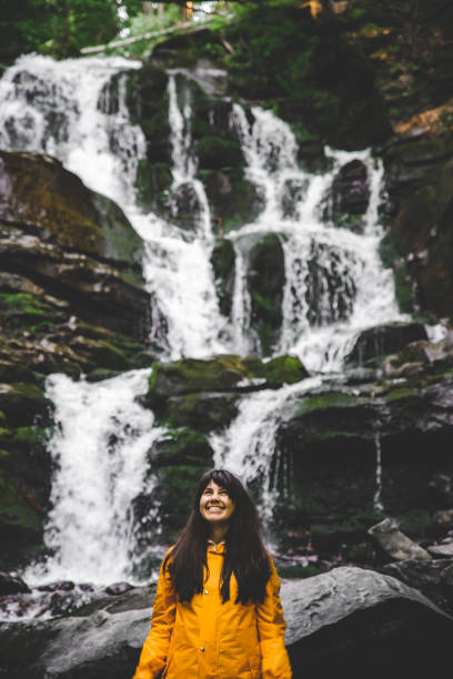 istock smiling woman in yellow raincoat with waterfall on background 1023895112