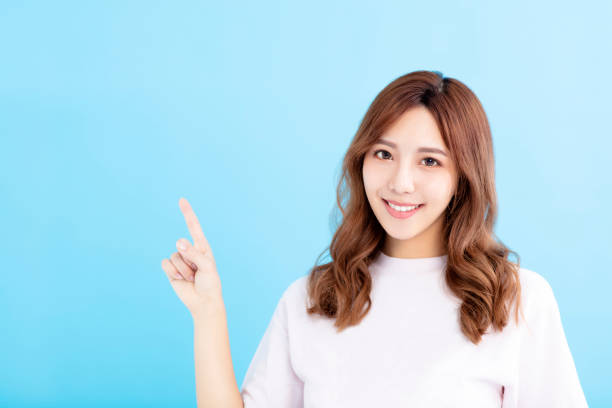 istock smiling Young woman pointing at blue background 1023914350