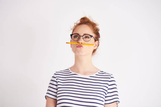 Bored woman having fun with pencil Bored woman having fun with pencil grimacing stock pictures, royalty-free photos & images