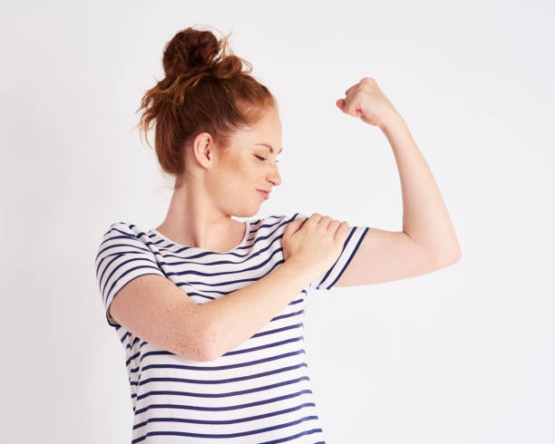 mujer confiada y fuerte mostrando sus bíceps en studio shot - human muscle women bicep girl power fotografías e imágenes de stock