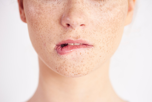 Part of woman biting her lip at studio shot