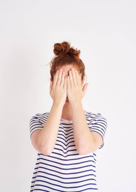 Woman covering her face with her hands at studio shot
