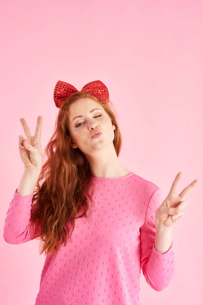 segno di pace fatto da giovane donna in studio girato - hair bow shirt bow one young woman only foto e immagini stock