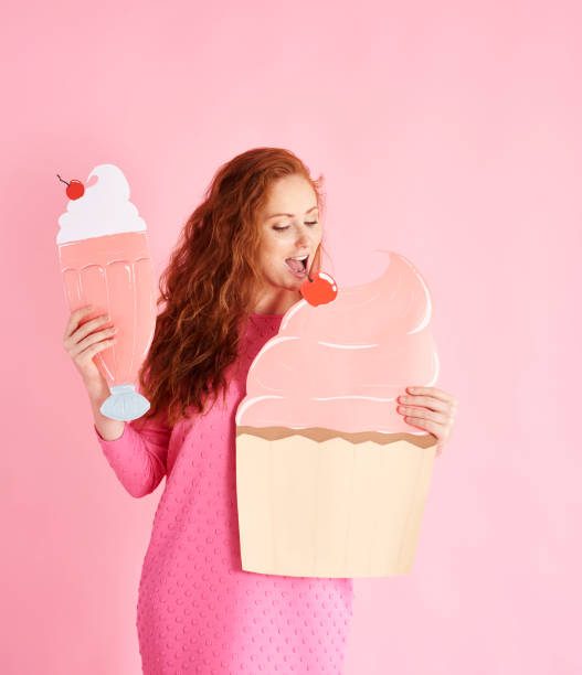 istock Young woman eating a cupcake at studio shot 1023938586