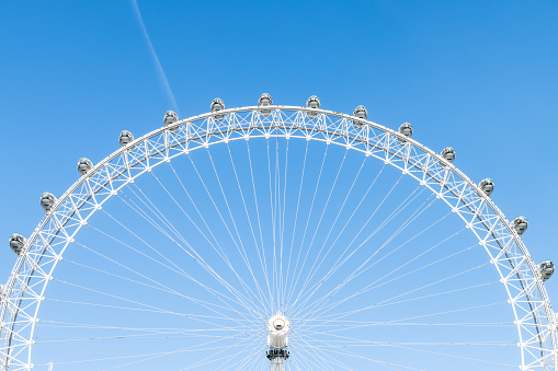London, UK - June 22, 2018: Closeup view of London Eye center with wires isolated against blue sky ferris wheel spinning