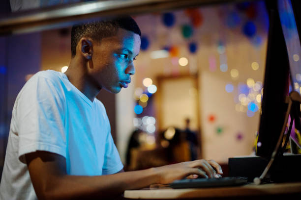 afro-américain garçon utilisant un ordinateur dans la nuit - addiction internet computer teenager photos et images de collection