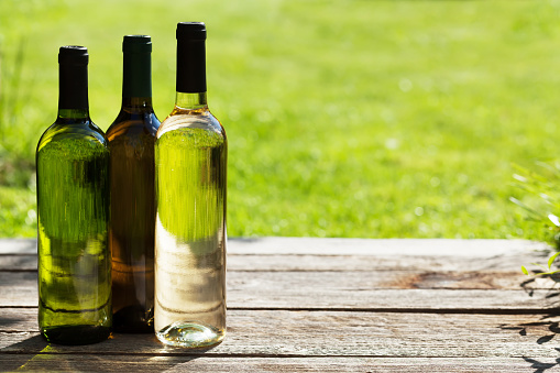 White wine bottles on wooden table. Outdoor still life. With space for your text