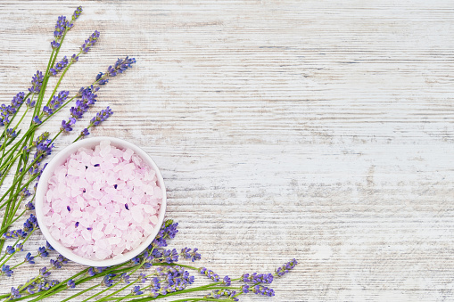 Essential lavender salt and lavender flowers on wooden background. SPA lavender products. Top view, copy space