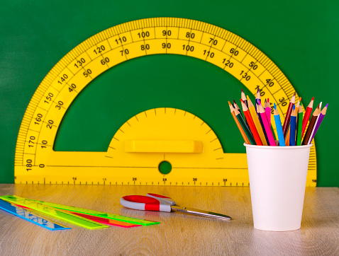 Escuela concepto colore lápiz, regla, tijeras y transportador amarillo en pizarra verde photo