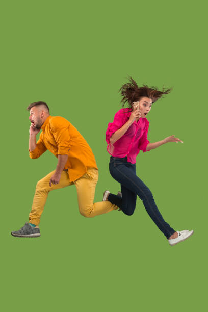 istock Full length of young couple with mobile phone while jumping 1023980464