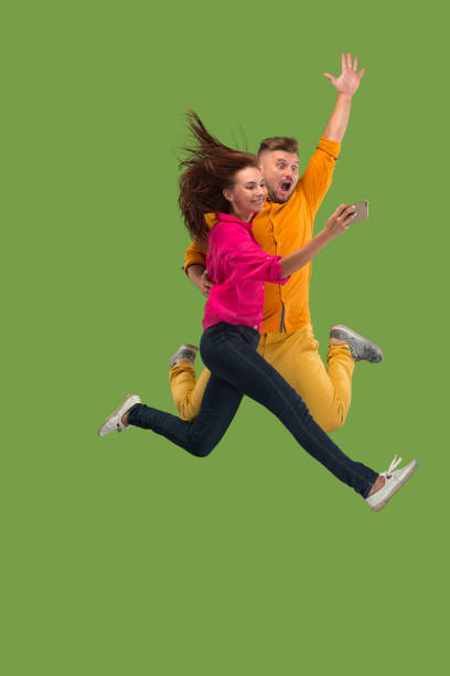 istock Full length of young couple with mobile phone while jumping 1023980572