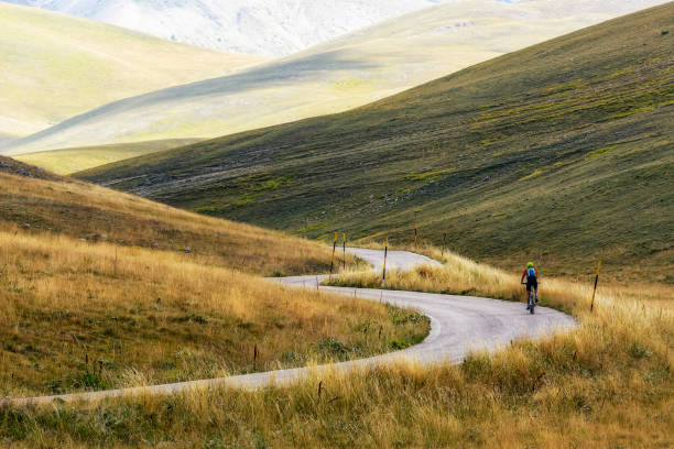 un ciclista isolato in salita su una strada di montagna di campo imperatore - abruzzo -italia - giro ditalia foto e immagini stock