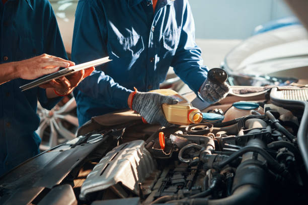 Pouring oil in engine Mechanic pouring oil in car engine when his colleague using tablet computer lubrication stock pictures, royalty-free photos & images