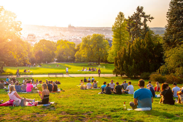 tramonto nei giardini rieger, sady riegrovy, a praga. molte persone sedute nell'erba e che si godono la soleggiata serata estiva e il belvedere del centro storico di praga. repubblica ceca - town of friendship foto e immagini stock