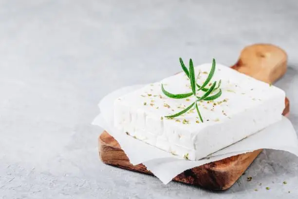 Homemade greek cheese feta with rosemary and herbs on wooden cutting board