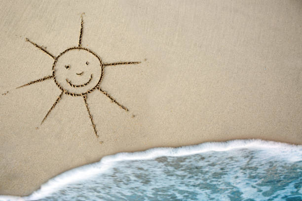 Sun in the sand on the beach.Sun drawn in the sand with wave rolling.