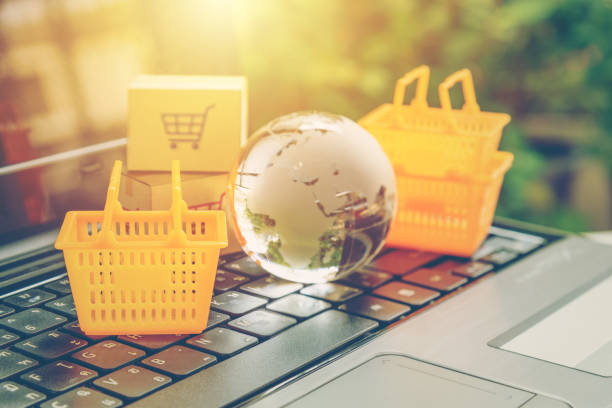 グローバルまたは世界中のオンライン ショッピング ・小売りの e コマースおよび配信・ サービス ・ コンセプト: バスケット、ラップトップ上の世界地図は、消費者購入を描写するか、また - catalog internet e commerce customer ストックフォトと画像