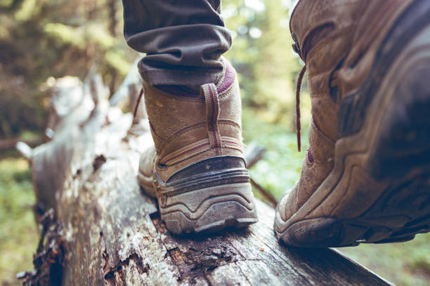 bottes de randonnée close-up. étapes touristiques fille sur un journal - european alps women summer outdoor pursuit photos et images de collection