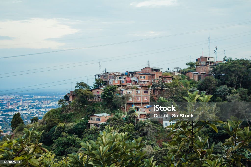 Isolated Colombian Village Shanty town homes in Colombia overlooking other buildings and houses in Colombia surrounded by nature. Copy space available, cloudy day, wires strung across the image. Cali - Colombia Stock Photo