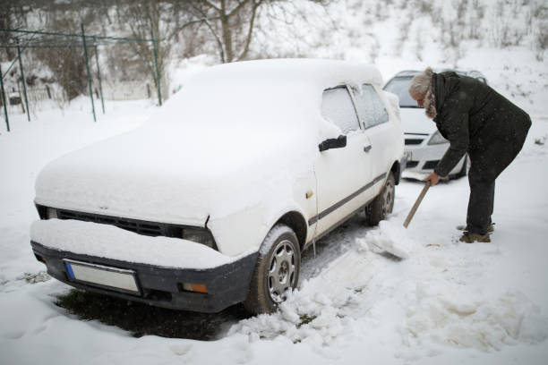 Stuck in snow. Senior man with shovel removing snow