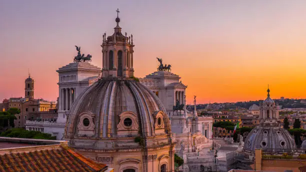 Beautiful sunset in Rome in orange, pink, purple and purple colors – a view of the landmarks and ancient architecture in the city center from the roof of the historic building