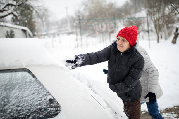 istock Mother and daughter cleaning snow-covered car 1024081878
