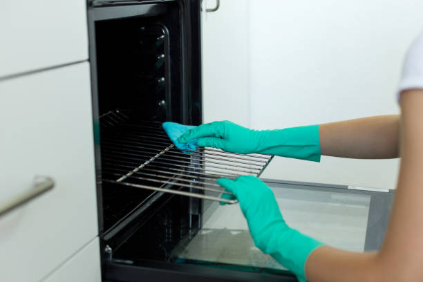 Woman hand in protective glove with rag cleaning oven Woman hand in protective glove with rag cleaning oven cleaning stove domestic kitchen human hand stock pictures, royalty-free photos & images