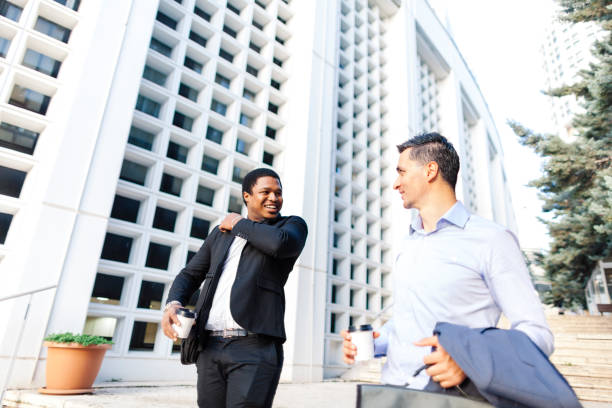 istock Two businessmen holding coffee and talking to each others while walking 1024090850
