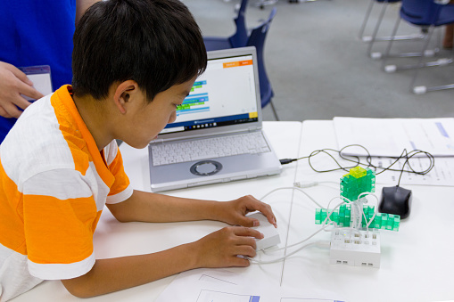 Japanese schoolboy with laptop in robotics class