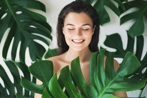 retrato de mujer joven y bella con la piel suave ideal en hojas tropicales - leaf epidermis fotografías e imágenes de stock