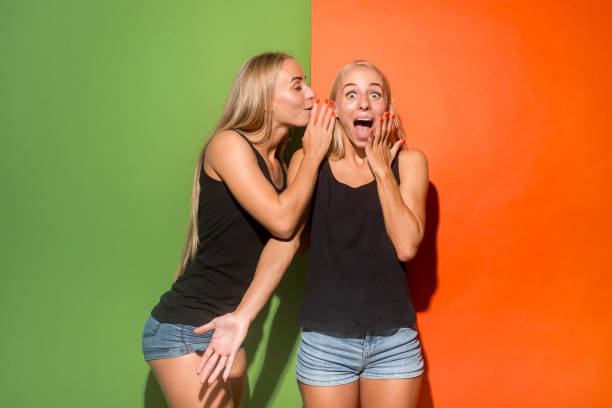istock The young woman whispering a secret behind her hand over studio background 1024105274