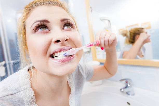 istock Woman brushing cleaning teeth in bathroom 1024105644