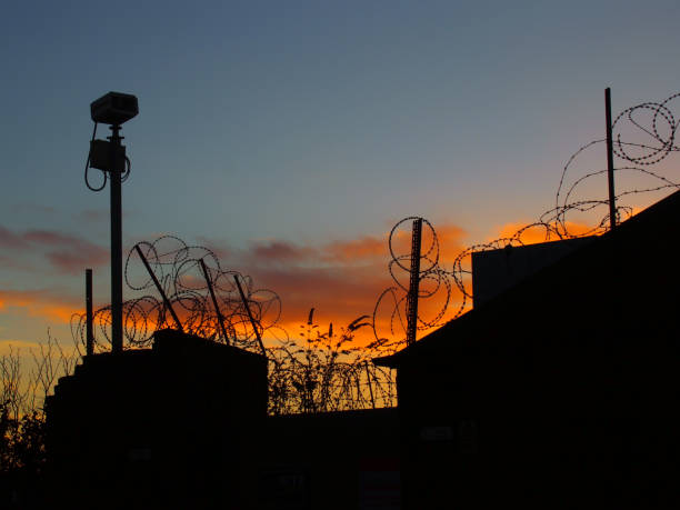 stacheldraht und überwachungskamera mit abendhimmel und sonnenuntergang - border control stock-fotos und bilder