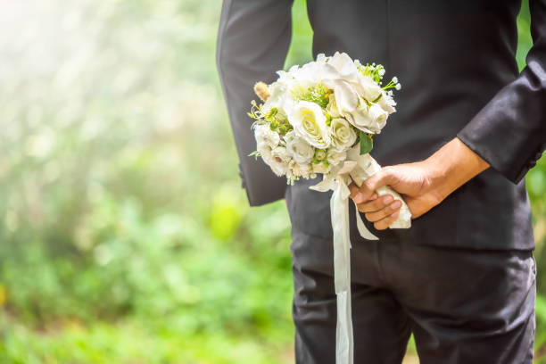 istock Selected focus on groom holding a white bouquet on back side for his bride on their ceremony. 1024119480