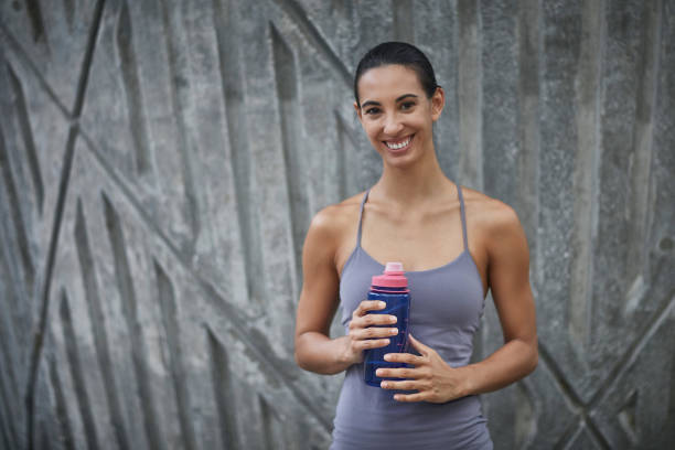 istock Smiling sportswoman with bottle against wall 1024120674