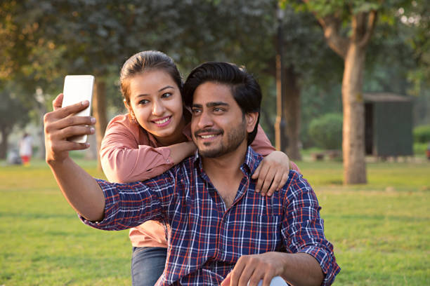 istock Beautiful young couple taking selfie in park - Stock image 1024127002