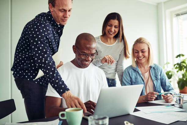 istock Smiling group of diverse work colleagues using a laptop together 1024129008