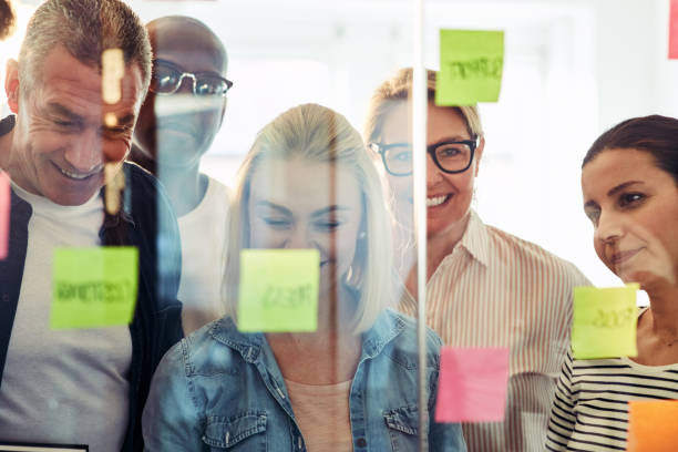 istock Smiling coworkers brainstorming with sticky notes on an office wall 1024129020