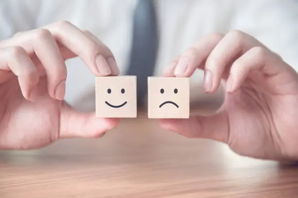 Photo of Close up smiley and sad face icon on wood cube, Service rating, satisfaction concept.